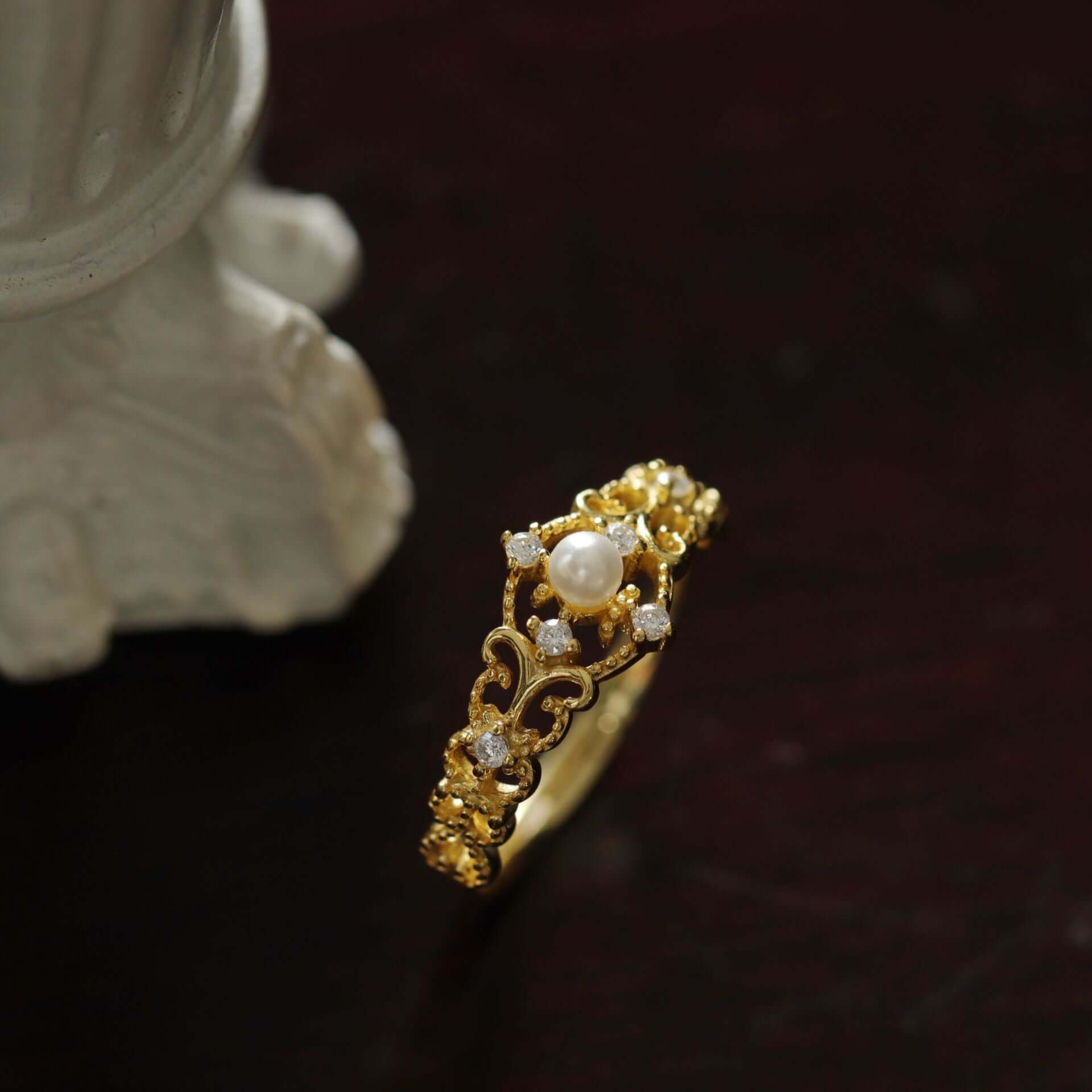 Elegant gold ring with pearl and sparkling stones, showcasing intricate design and adjustable fit.
