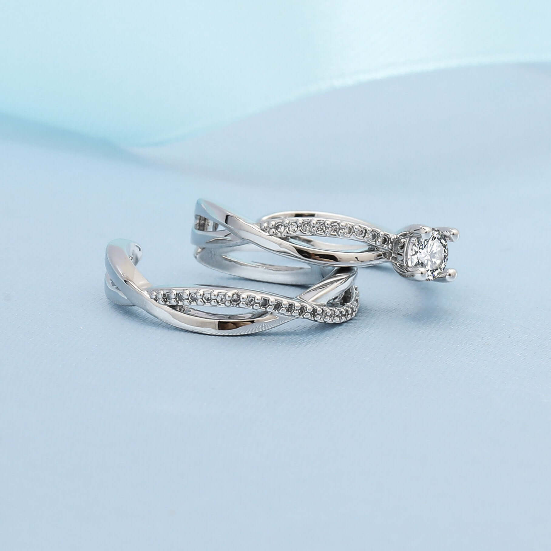 My Store elegant silver couple ring set featuring twisted diamond bands and solitaire on pale blue backdrop